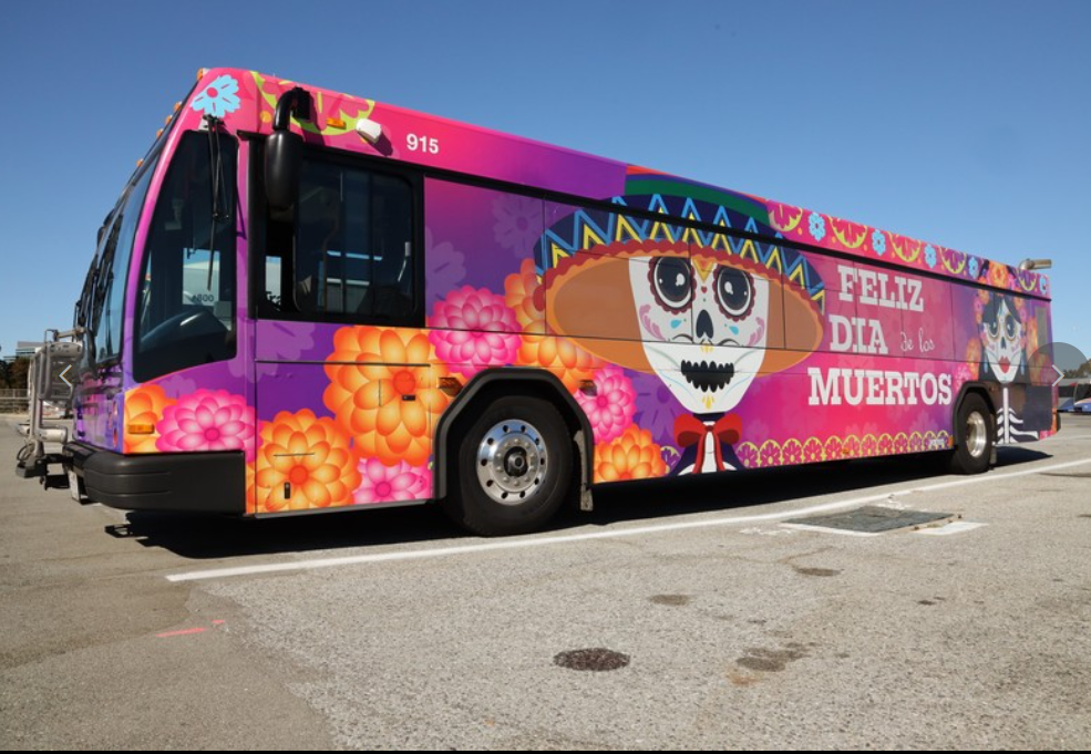 A SamTrans bus decorated (or wrapped) with Día de Muertos art on the sides