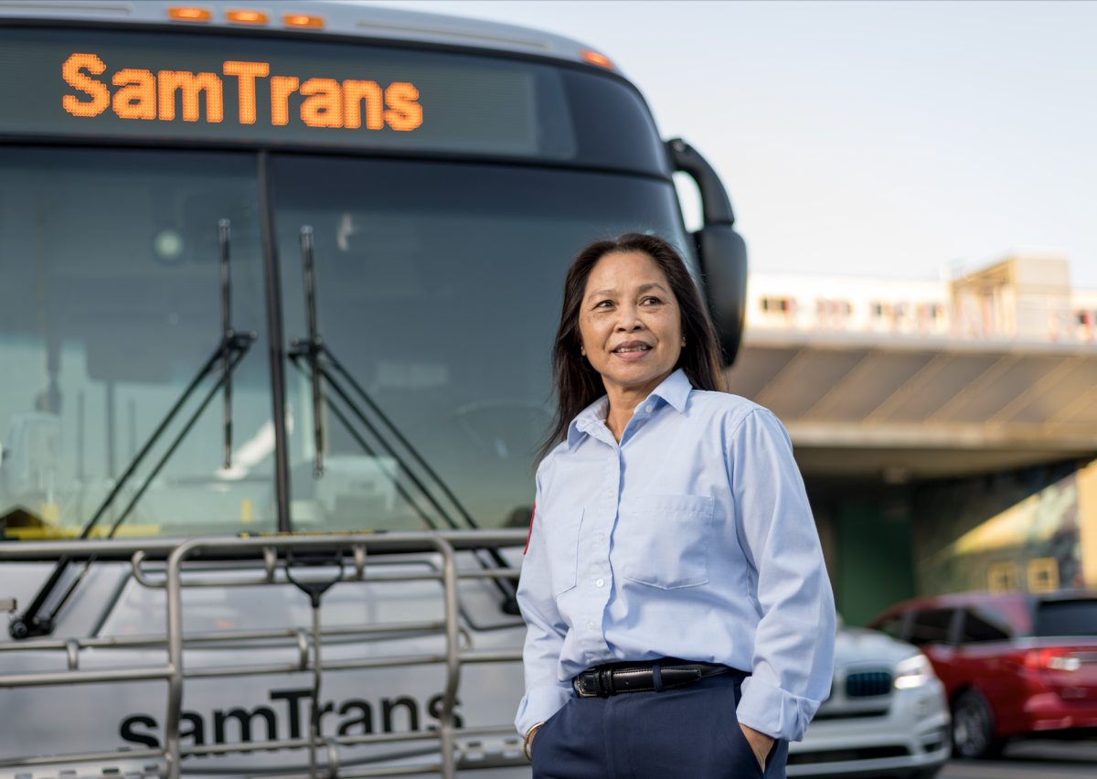 A SamTrans operator stands in front of her bus