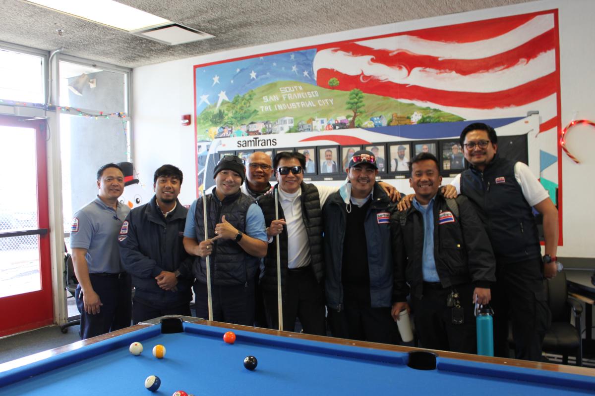 Filipino SamTrans bus operators gather around a pool table