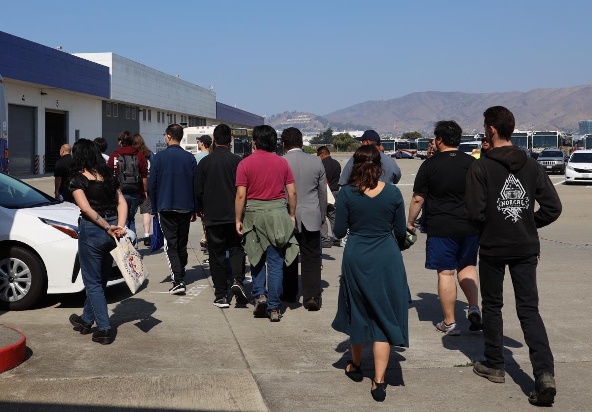 A group of people are escorted into one of the main buildings at North Base.